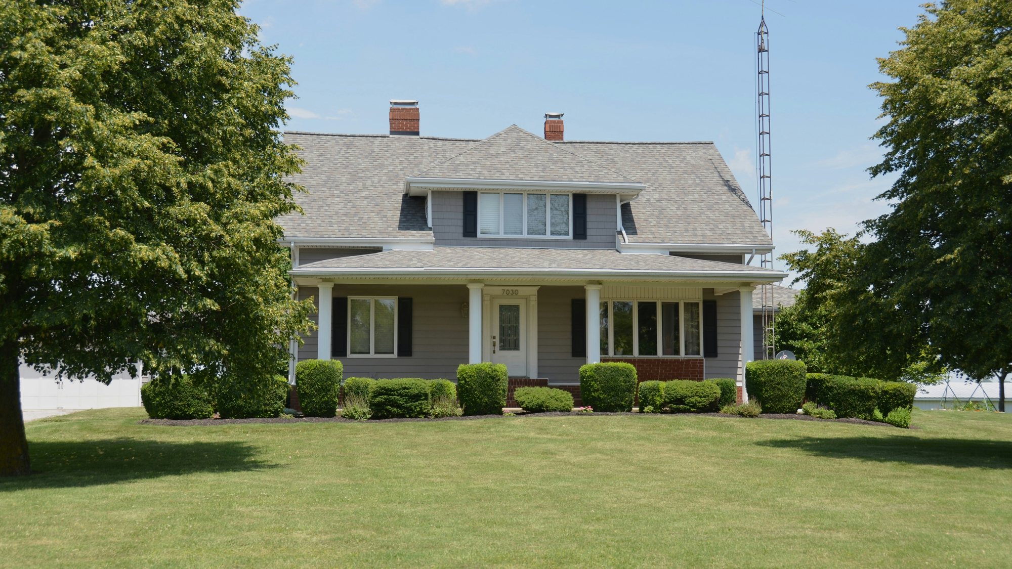 A gray house with a porch behind a wide green lawn