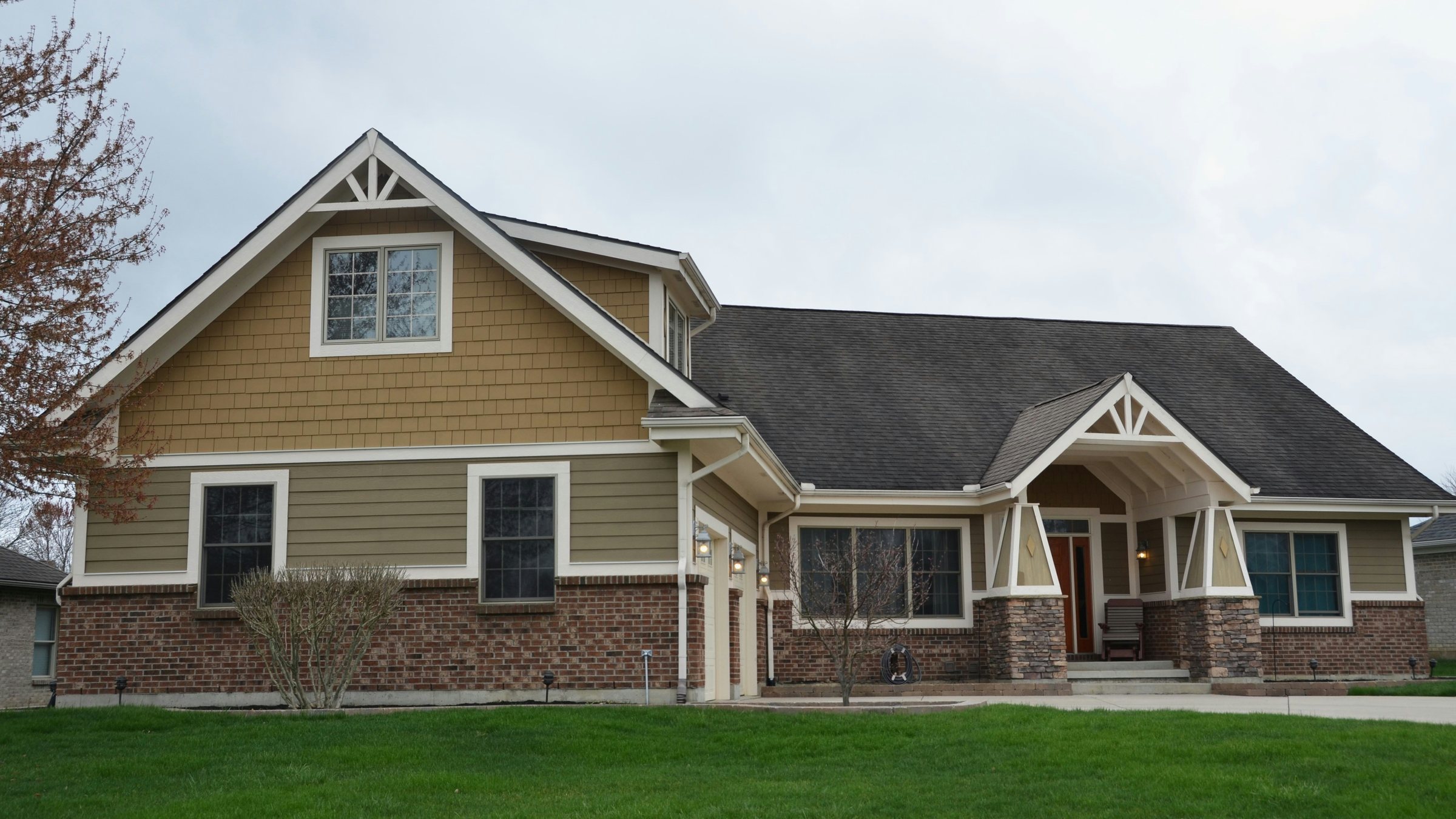 A tan and brick house with a green lawn