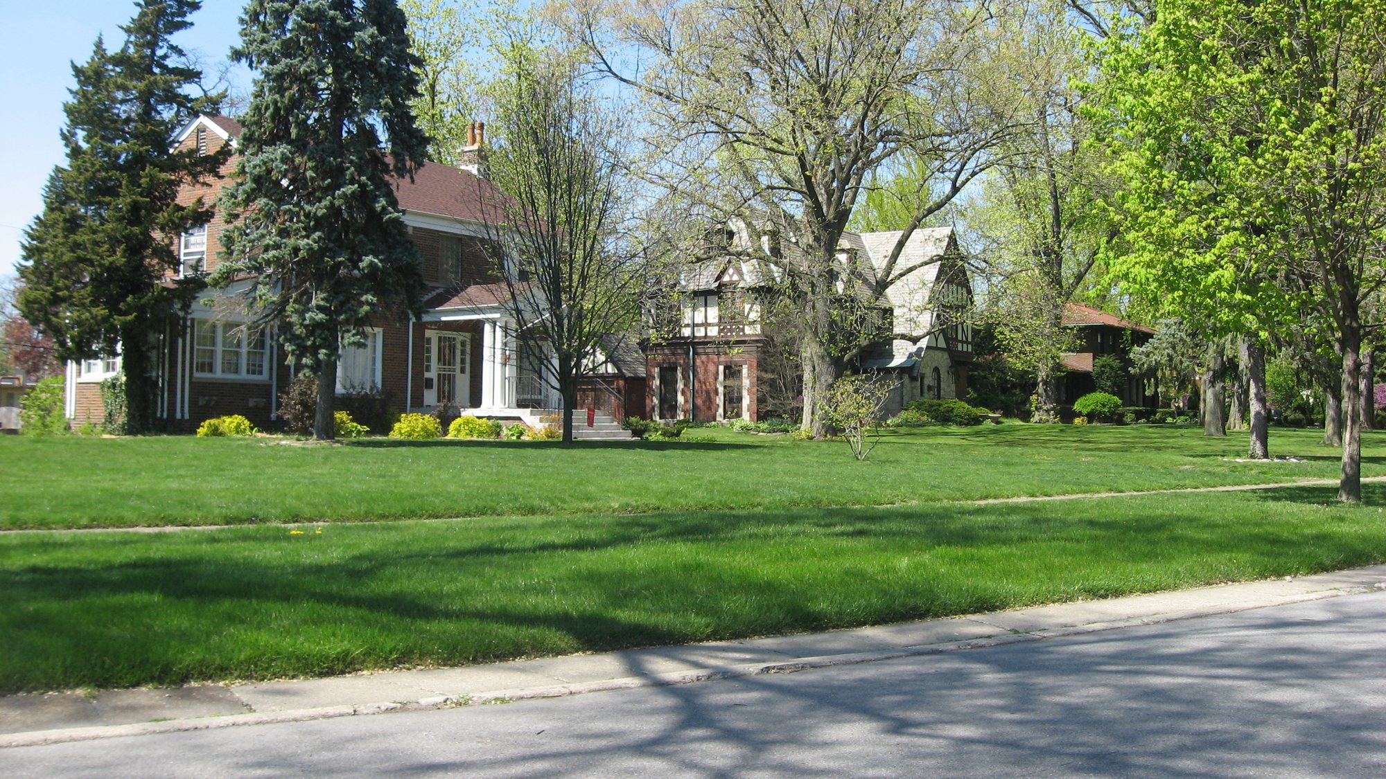A gray house with a porch behind a wide green lawn