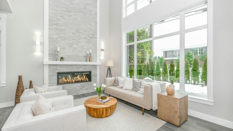 A bright two-story living room with a stone fireplace and tall windows