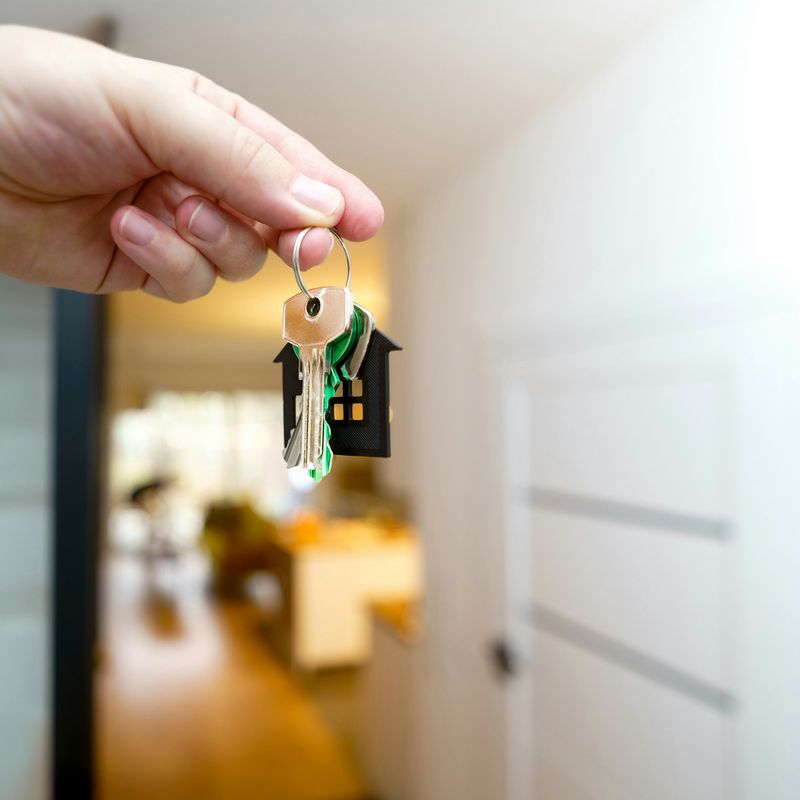 A hand holding house keys at an open front door